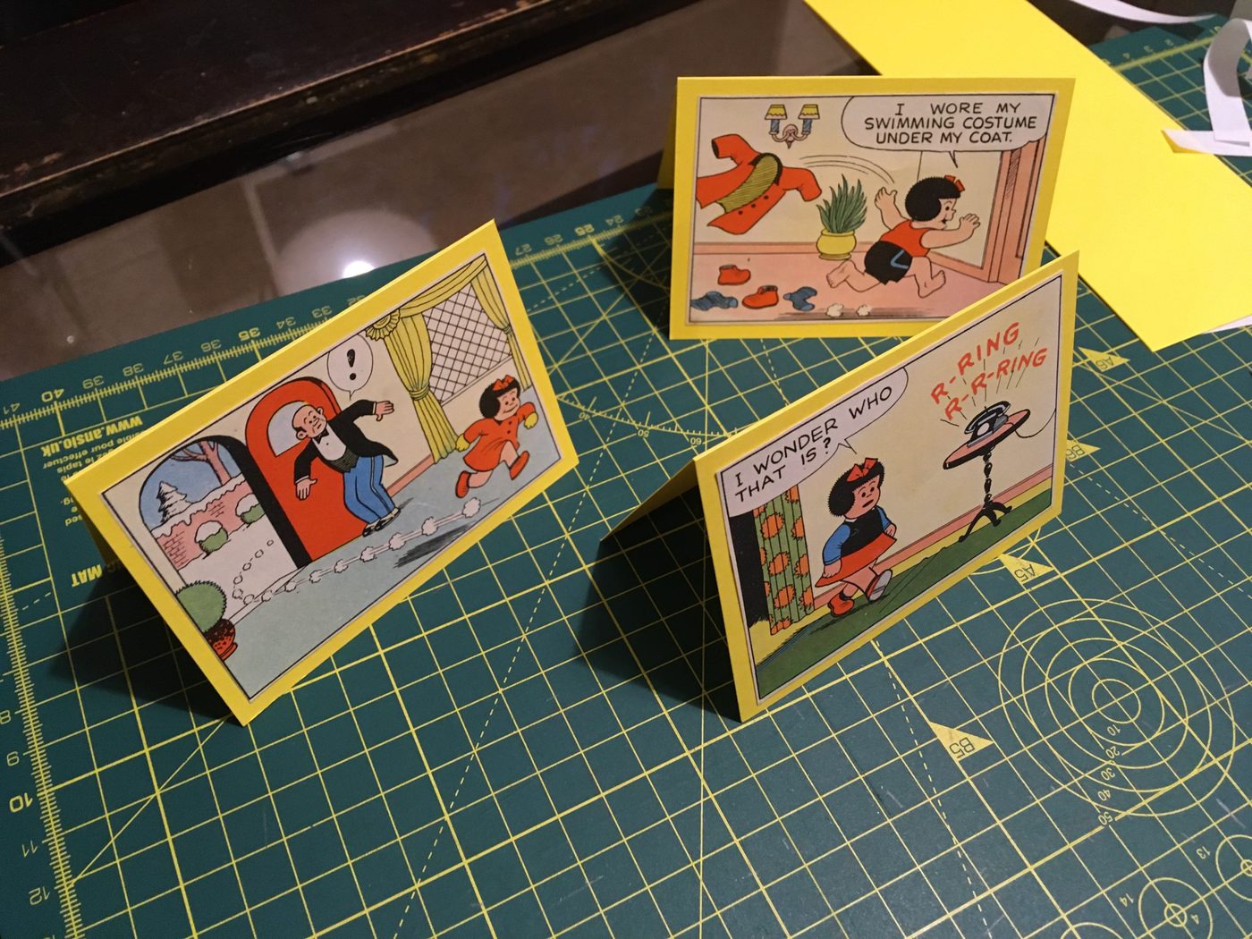 Three completed yellow greeting cards laid out on a cutting mat