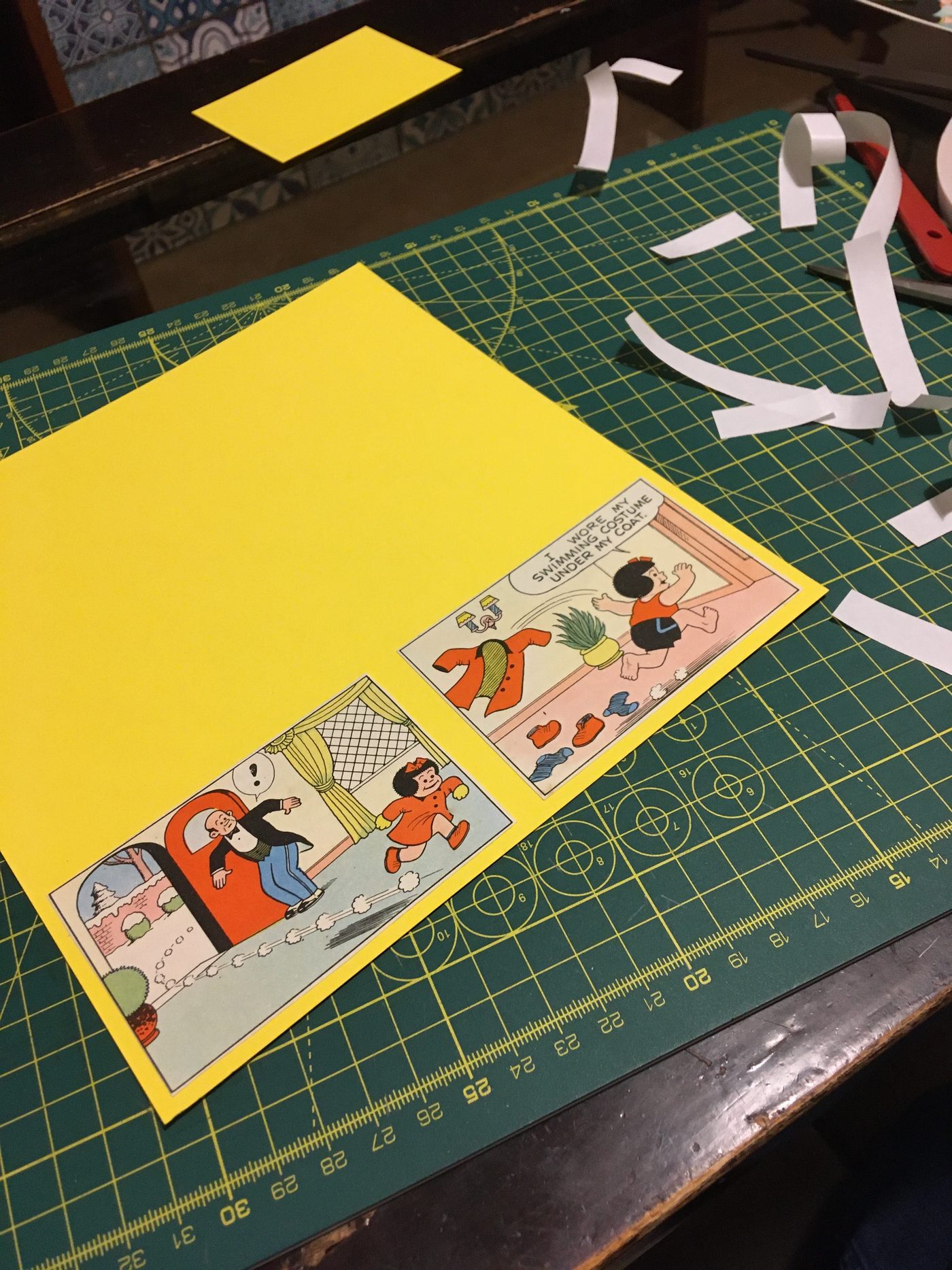 Vintage comic panels being arranged on yellow card on a cutting mat