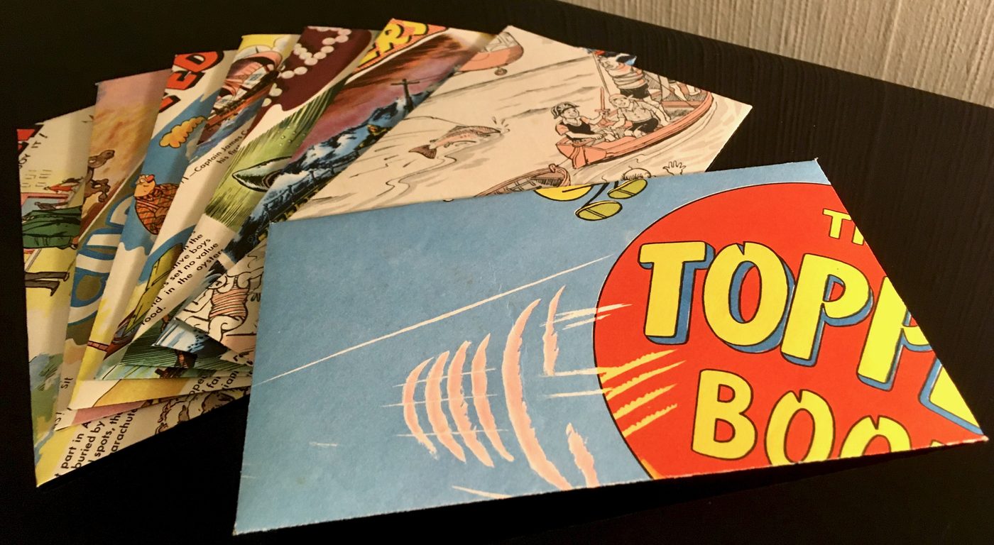 A stack of handmade envelopes folded from colourful vintage comic pages