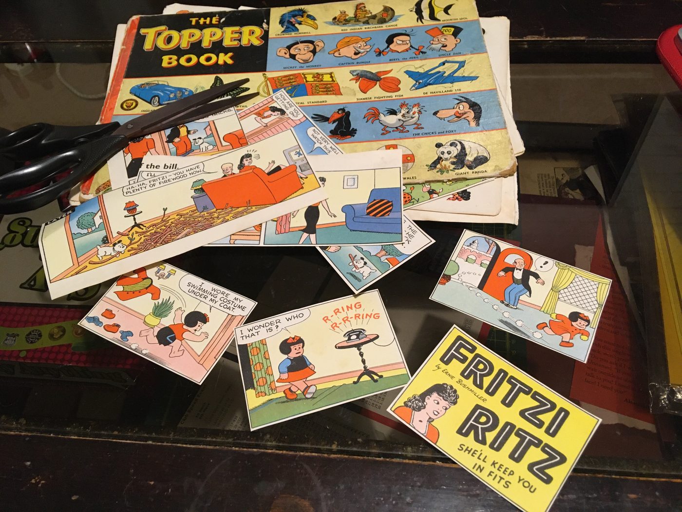 A worn vintage Topper annual beside cut-out comic panels and a pair of scissors