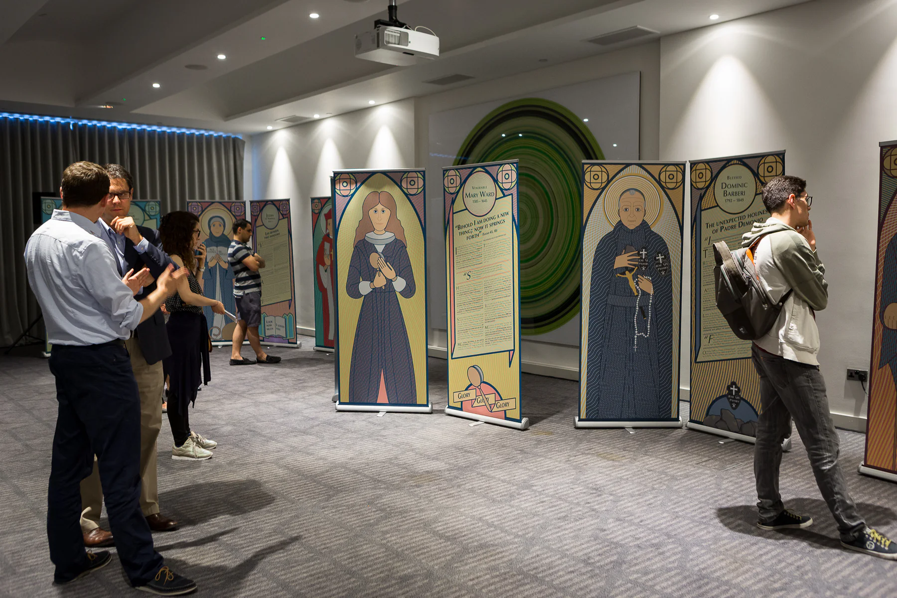 Visitors moving among the Holy Unexpected exhibition panels